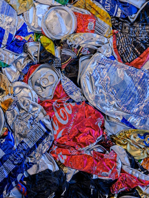 A large outdoor area is filled with an array of waste and recyclable materials, primarily consisting of numerous neatly stacked cardboard boxes of fresh fruit produce, displaying bright red, yellow, a